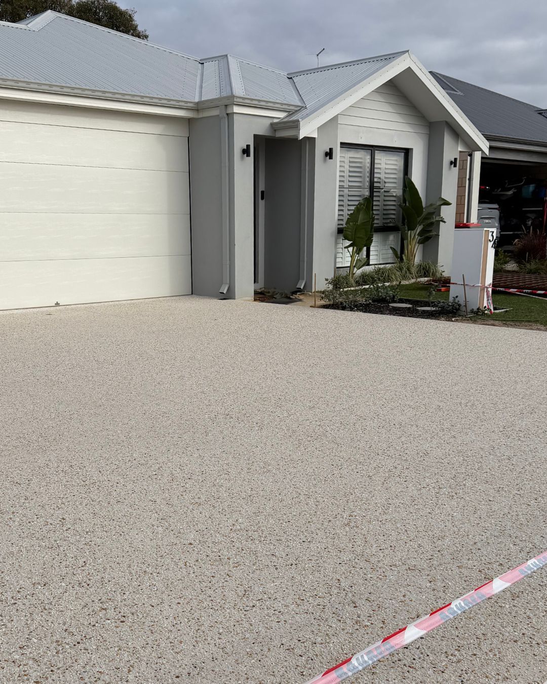 New exposed aggregate concrete driveway in front of a modern home