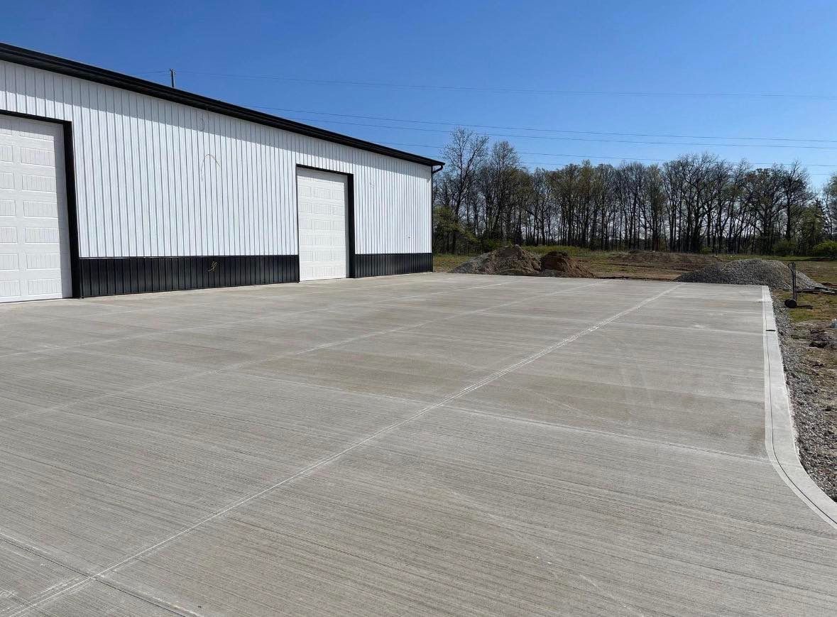 Large finished concrete slab in front of a metal shop building